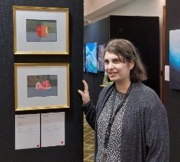 Woman standing next to two framed pastel drawings